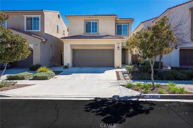 mediterranean / spanish home featuring a garage, concrete driveway, a tile roof, and stucco siding