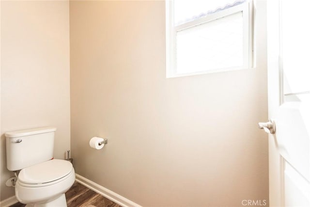 bathroom with toilet, baseboards, and wood finished floors