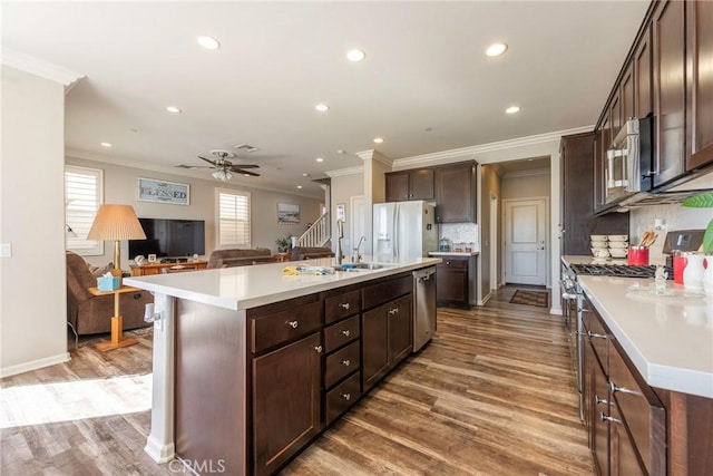 kitchen featuring appliances with stainless steel finishes, light countertops, open floor plan, and a kitchen island with sink