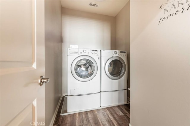 clothes washing area with laundry area, baseboards, visible vents, washer and clothes dryer, and wood finished floors