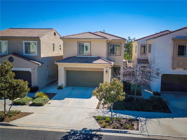 mediterranean / spanish-style home with driveway, a tiled roof, an attached garage, and stucco siding