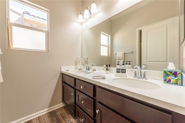 bathroom featuring wood finished floors, a sink, baseboards, and double vanity