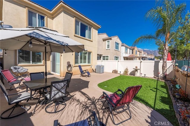 back of property with stucco siding, a patio area, central AC, a residential view, and a fenced backyard