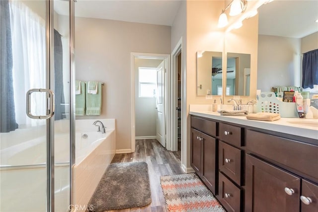 full bath featuring a garden tub, a sink, wood finished floors, double vanity, and a stall shower