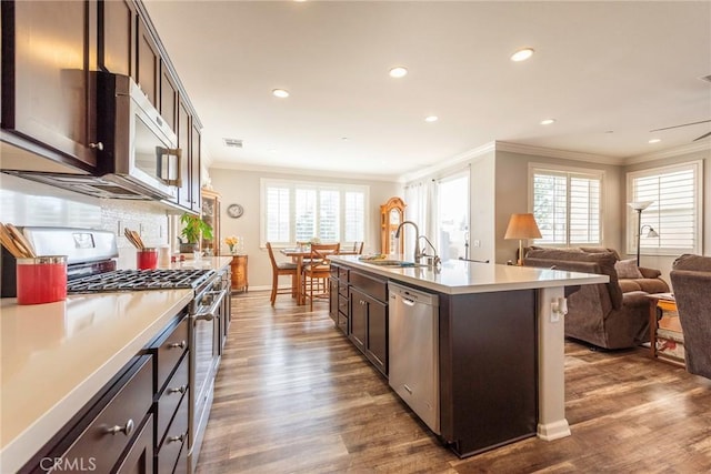 kitchen featuring a center island with sink, stainless steel appliances, light countertops, open floor plan, and a sink