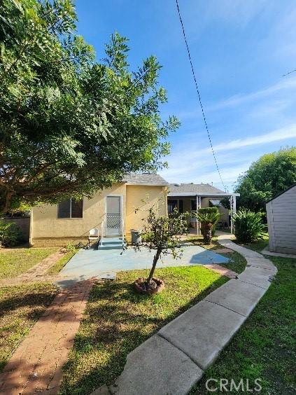 view of front of home featuring entry steps, a front yard, and stucco siding