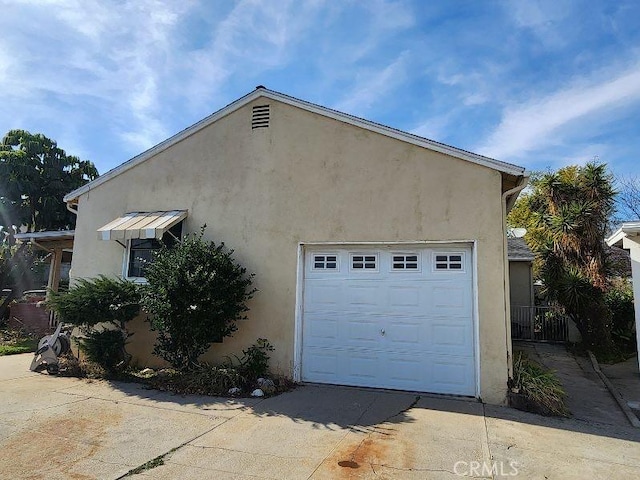 view of side of home featuring a garage, driveway, and stucco siding