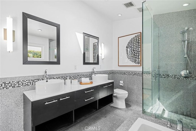 full bath featuring a wainscoted wall, a shower stall, tile walls, and a sink