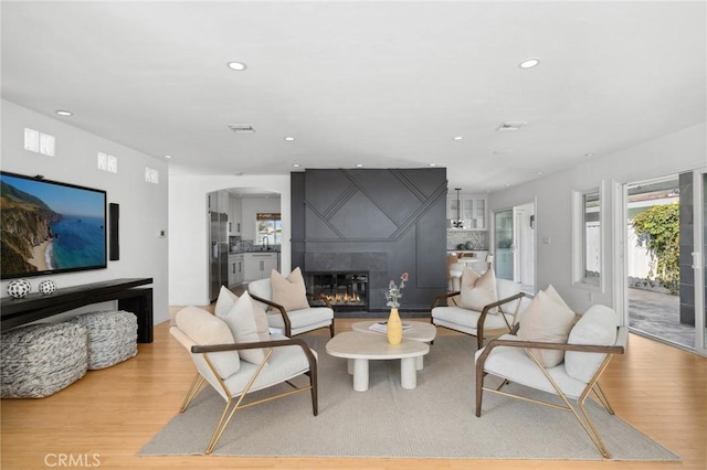 living area featuring recessed lighting, a fireplace, arched walkways, and light wood finished floors