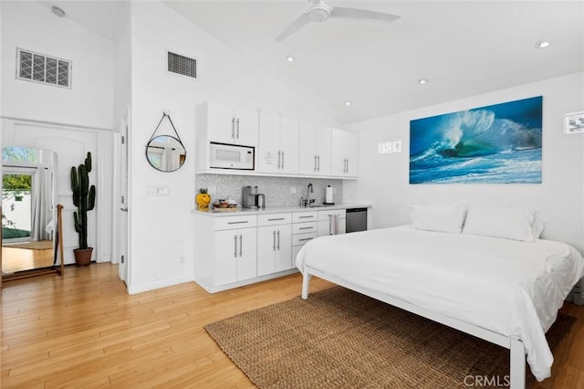 bedroom featuring a sink, visible vents, high vaulted ceiling, and light wood finished floors