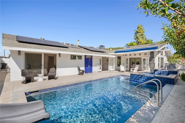 back of property featuring stucco siding, solar panels, and a patio