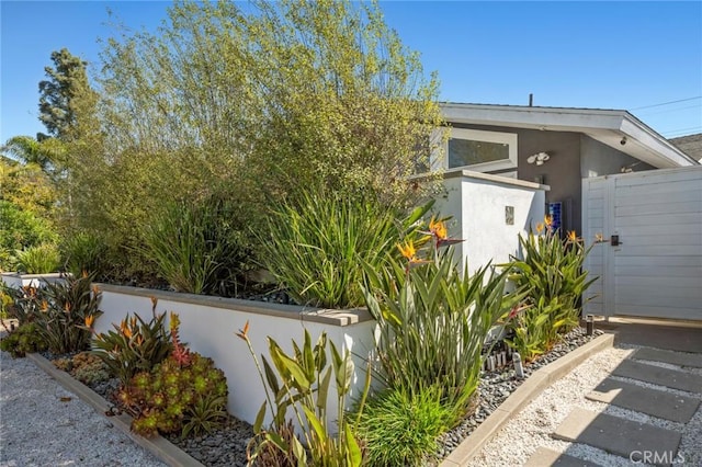 exterior space with stucco siding, fence, and a gate