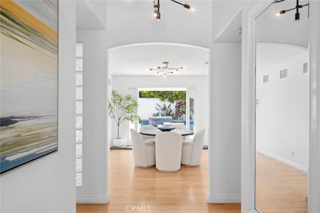 dining area featuring arched walkways, visible vents, baseboards, and wood finished floors