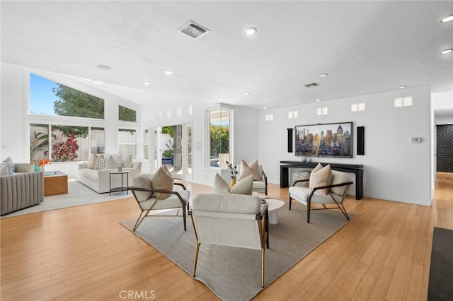 living area with visible vents, recessed lighting, light wood-type flooring, and vaulted ceiling