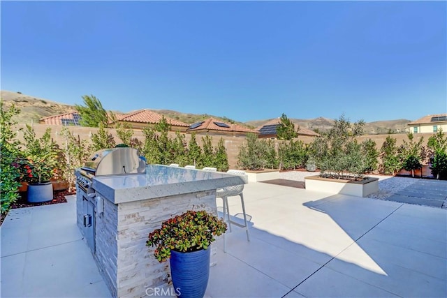 view of patio with a fenced backyard, a mountain view, outdoor dry bar, and area for grilling