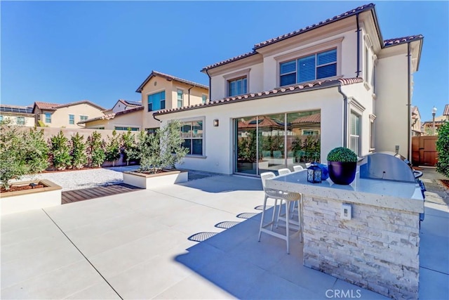 back of house with a patio, an outdoor kitchen, outdoor dry bar, a tiled roof, and stucco siding