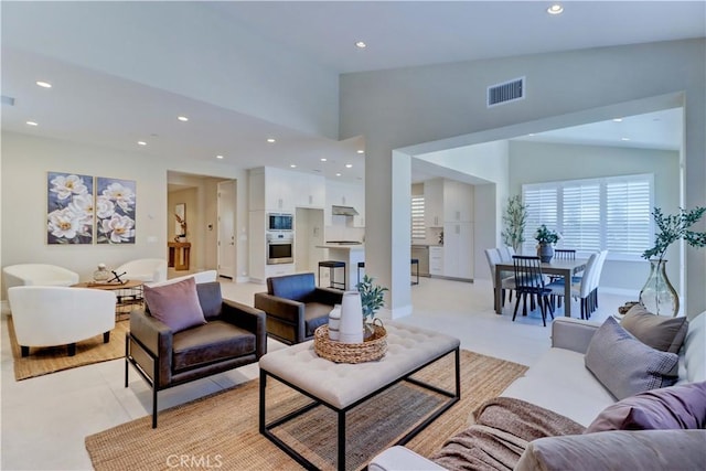 living room featuring baseboards, a high ceiling, visible vents, and recessed lighting