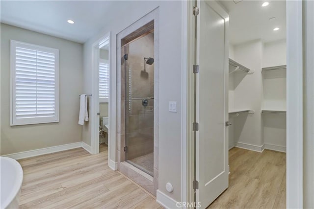 bathroom with a shower stall, toilet, and wood finished floors