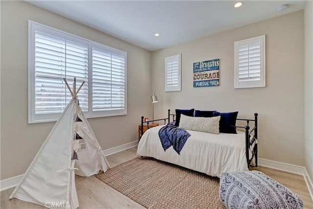 bedroom with baseboards, wood finished floors, and recessed lighting