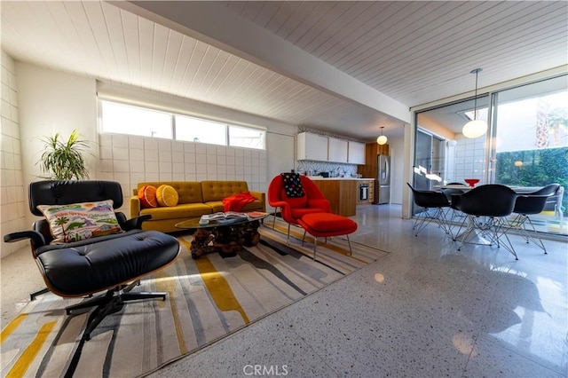 living area with light speckled floor and beam ceiling