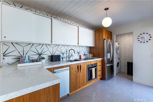 kitchen with oven, stacked washer and dryer, white cabinetry, hanging light fixtures, and light countertops