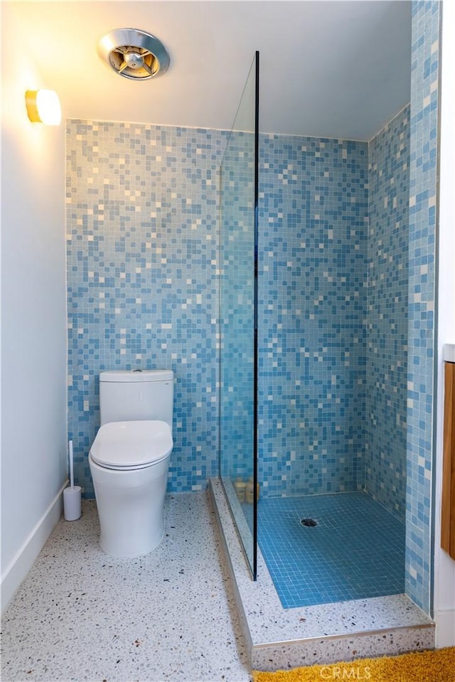 full bath with toilet, a shower stall, baseboards, and speckled floor