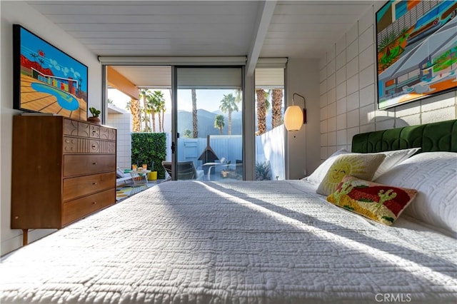 bedroom featuring access to exterior, floor to ceiling windows, a mountain view, and tile walls