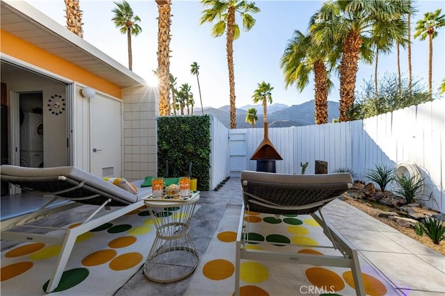 view of patio / terrace featuring a fenced backyard, a mountain view, and stacked washer / drying machine