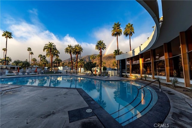 pool at dusk featuring a patio area, a community pool, and a mountain view