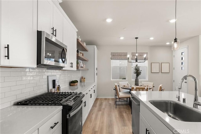 kitchen featuring open shelves, white cabinetry, stainless steel appliances, and a sink