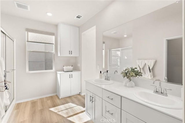 full bathroom featuring visible vents, wood finished floors, a sink, and a stall shower