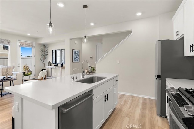 kitchen featuring appliances with stainless steel finishes, light wood-type flooring, white cabinets, and a sink