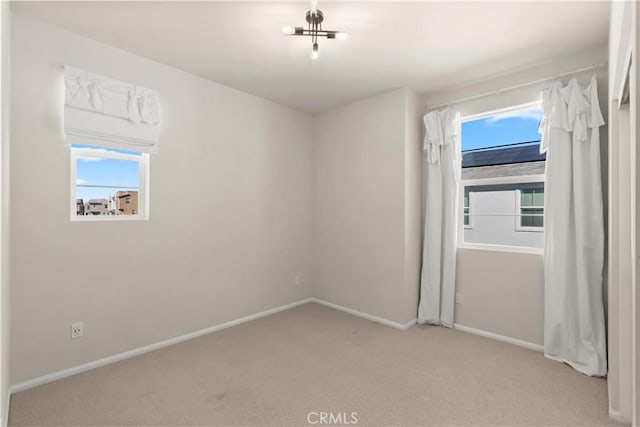 carpeted spare room featuring baseboards and a wealth of natural light