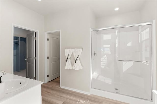 full bathroom featuring recessed lighting, wood finished floors, vanity, baseboards, and a stall shower