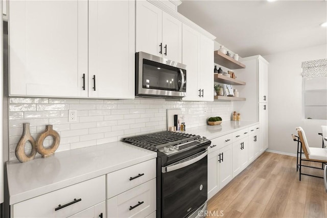 kitchen featuring white cabinets, stainless steel appliances, light wood-style floors, open shelves, and light countertops