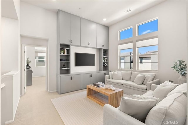 living room with light carpet, plenty of natural light, a towering ceiling, and visible vents