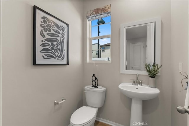 bathroom with toilet, a sink, and baseboards