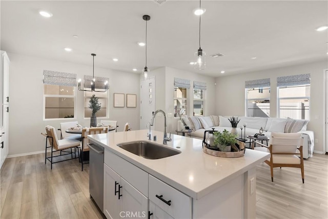 kitchen featuring dishwasher, light wood-style flooring, open floor plan, light countertops, and a sink