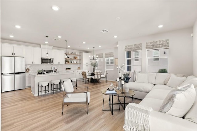 living area with recessed lighting, visible vents, and light wood-style flooring