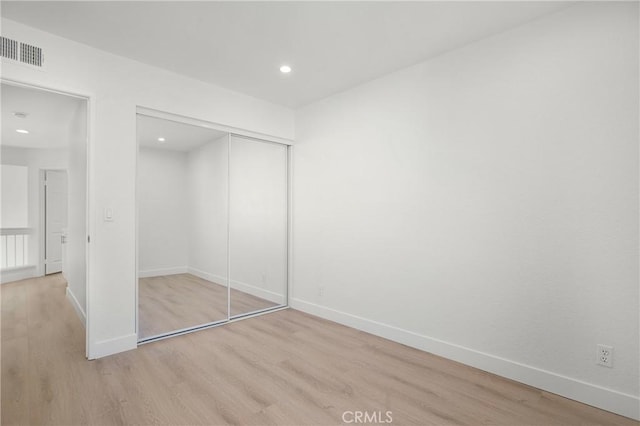 unfurnished bedroom featuring recessed lighting, a closet, visible vents, light wood-type flooring, and baseboards