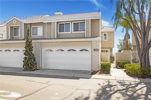 multi unit property with a garage, concrete driveway, a chimney, and stucco siding