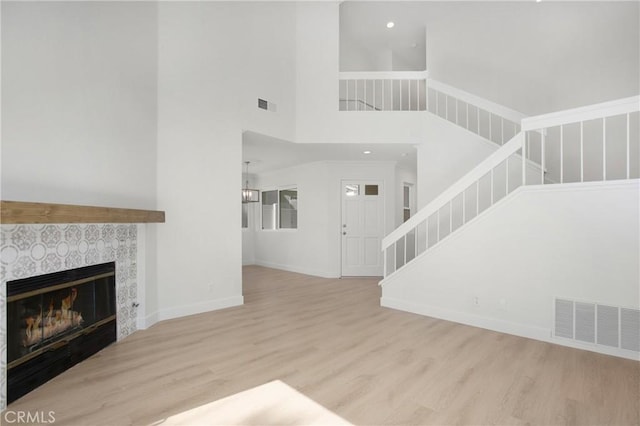 living room with light wood-type flooring, stairway, a fireplace, and visible vents