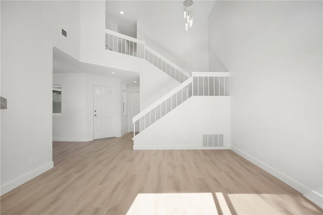 unfurnished living room featuring stairway, light wood-style flooring, visible vents, and baseboards