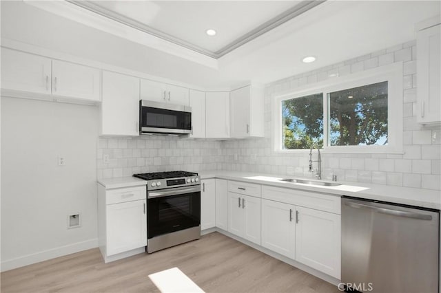 kitchen with white cabinetry, appliances with stainless steel finishes, light countertops, and a sink