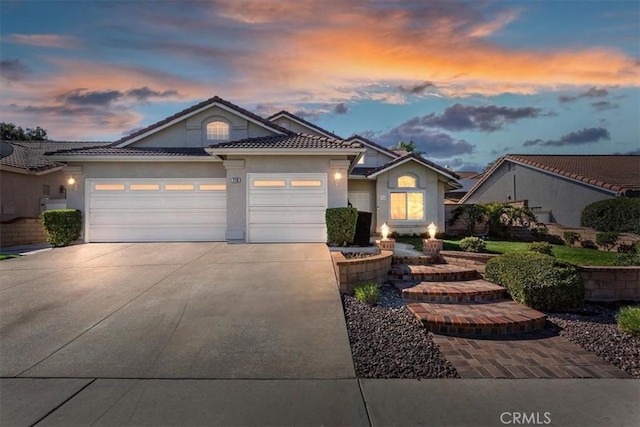 ranch-style home featuring a garage, driveway, a tile roof, and stucco siding