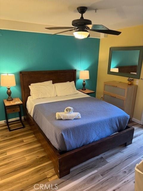 bedroom featuring ceiling fan, baseboards, and wood finished floors