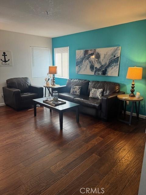 living area with dark wood-type flooring and baseboards