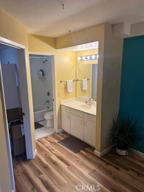 bathroom with baseboards, toilet, wood finished floors, bathtub / shower combination, and vanity