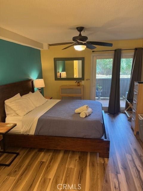 bedroom with access to exterior, a ceiling fan, and wood finished floors