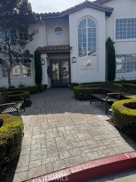 property entrance with stucco siding, a tile roof, a patio, and french doors